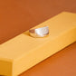Silver ring on a yellow stand against a brown background
