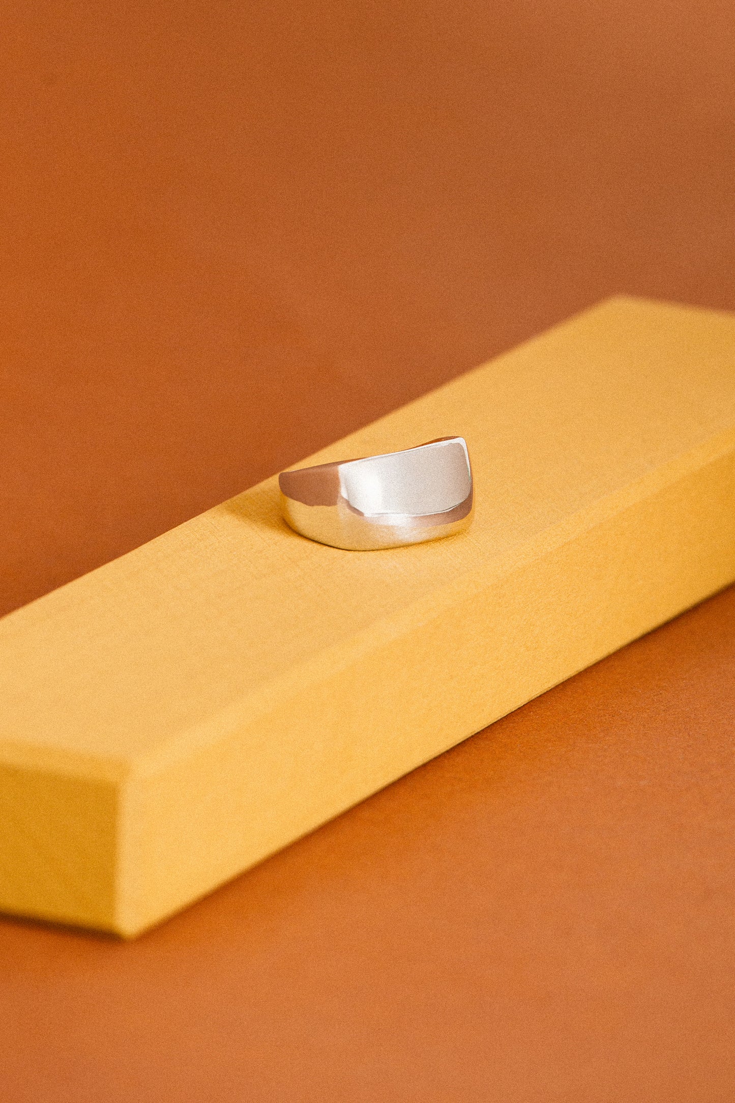 Silver ring on a yellow stand against a brown background